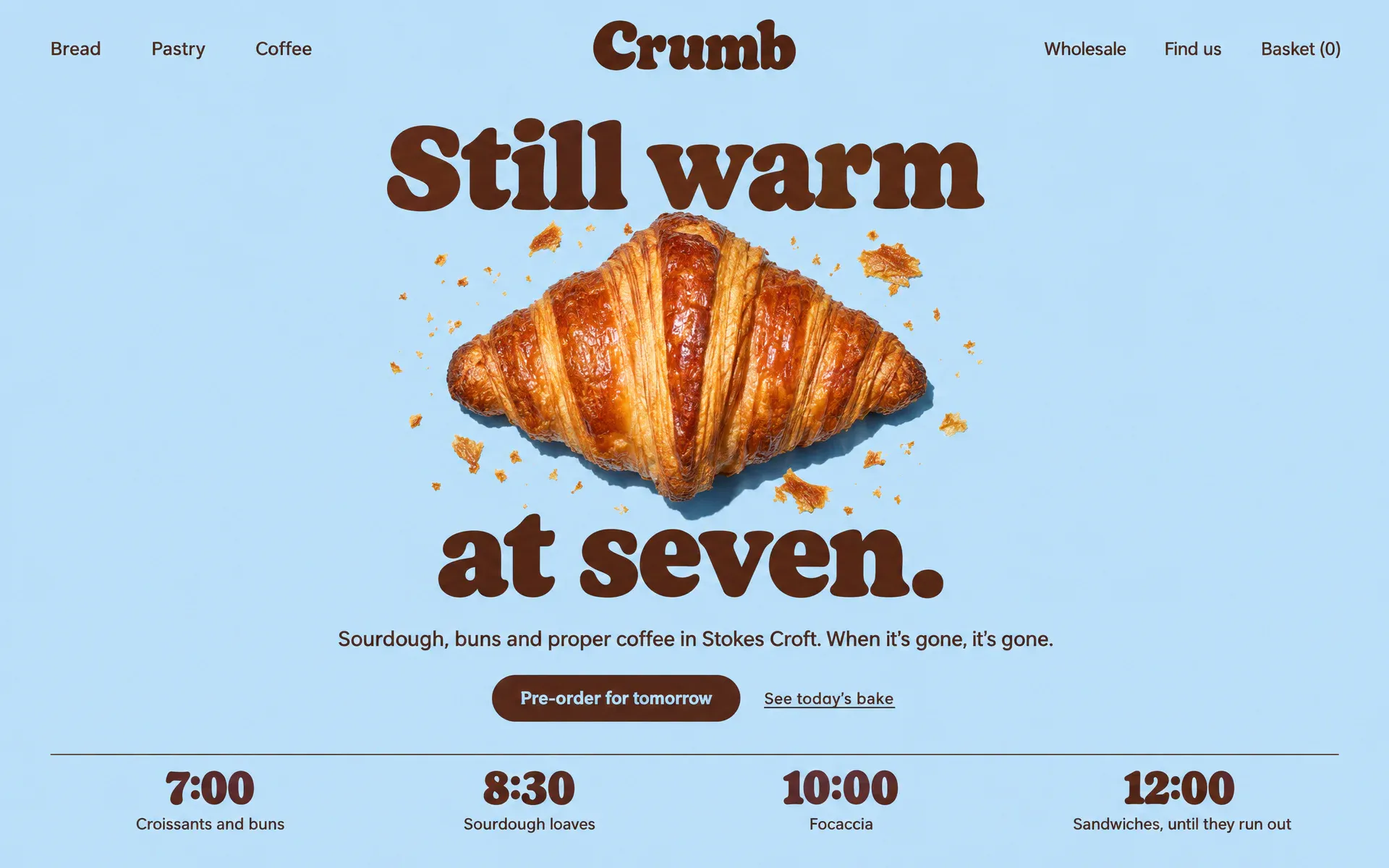 A bakery site on powder blue: one huge golden croissant in the centre with the headline Still warm at seven. split around it, and four bake times along the bottom